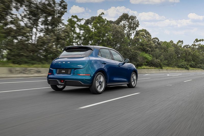 Rear three-quarter view of the GWM Ora hatchback driving on a test track.