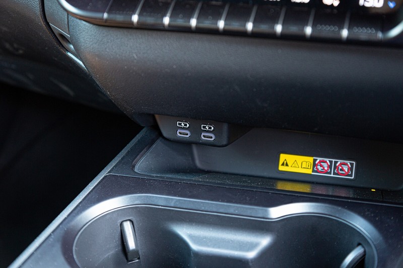 A pair of USB C ports, a wireless charging pad and drinks holders of the Lexus UX 250h EX (2023).